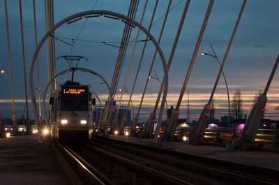 Cable car against sky during sunset at railway bridge in city