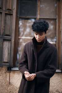 Portrait of young woman standing against wall