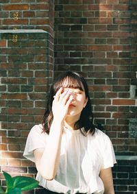 Portrait of woman against brick wall