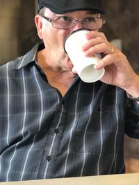 Man looking away while drinking coffee in cup