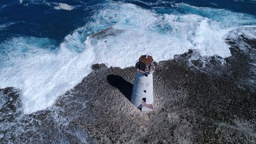 High angle view of man standing on rock by sea