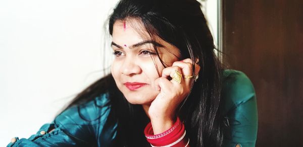 Portrait of beautiful young woman holding wall at home