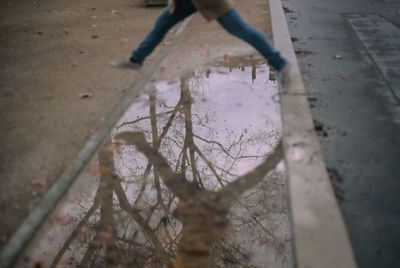 Low section of person standing by puddle on street