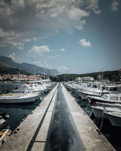 Sailboats moored at harbor against sky