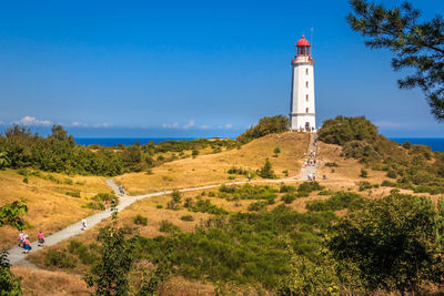 Lighthouse amidst trees and buildings against sky