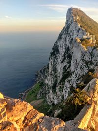 Scenic view of sea by cliff against sky