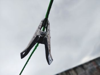 Low angle view of clothespins on rope against sky