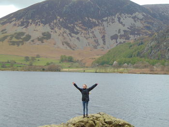 Man standing on mountain by lake against mountains