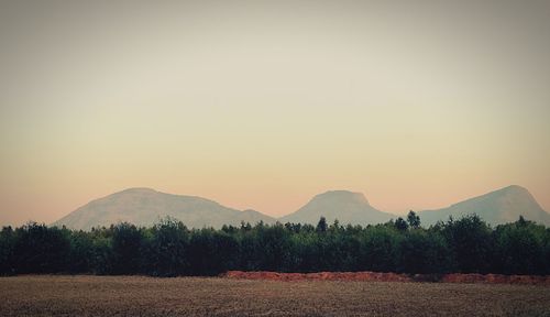 Scenic view of field by mountains against clear sky