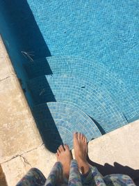 Low section of woman standing against swimming pool