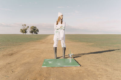 Young woman standing on green painting on dry field