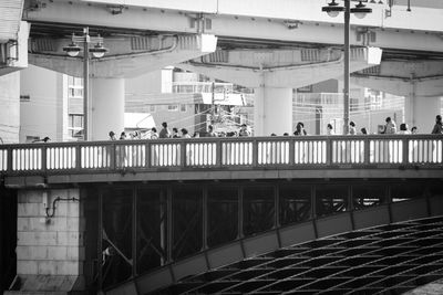 People on bridge by buildings in city