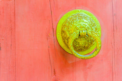 Close-up of green door knocker on wooden wall