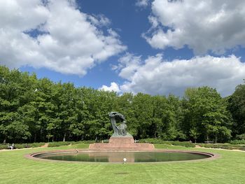 Statue against trees and plants against sky