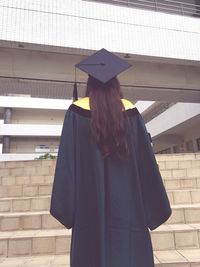 Rear view of woman standing against wall