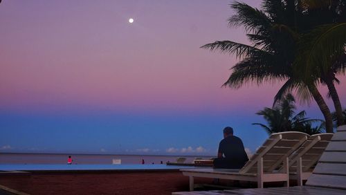 Man sitting on rooftop against sky