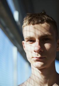 Portrait of young man standing by window