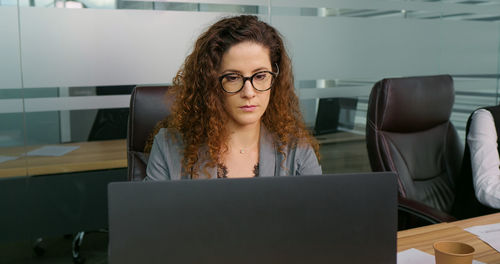 Concentrated woman working online on computer at office. 