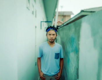 Portrait of young man standing against wall