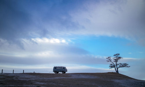 Van on field against sky during winter