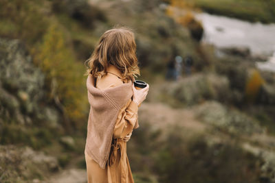 A pretty girl enjoys solitude drinks coffee walks in the autumn forest in nature in fall