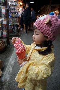 Side view of girl holding ice cream outdoors