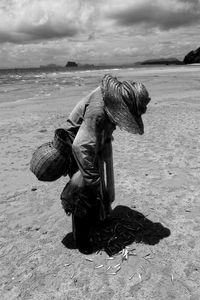 Man holding umbrella on beach against sky