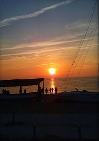 Silhouette sailboat on beach against sky during sunset