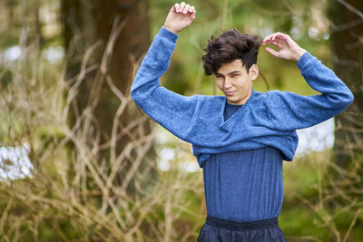 Young man wearing sweater while standing at forest