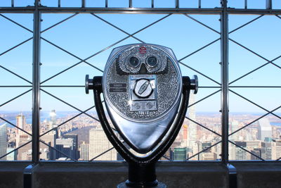 Close-up of coin-operated binoculars against cityscape