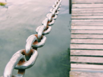 Close-up of rusty chain over lake