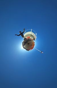 Low angle view of person paragliding against clear blue sky