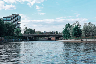 Bridge over river in city against sky