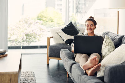 Woman using mobile phone while sitting in laptop