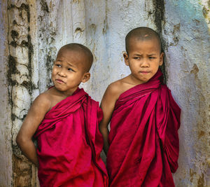 Monks in traditional clothing standing against wall