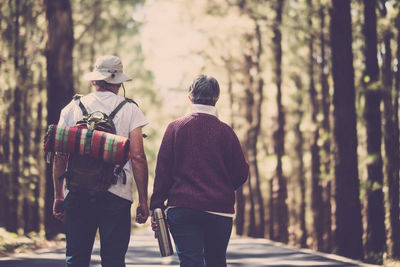 Rear view of people walking on street amidst trees in forest