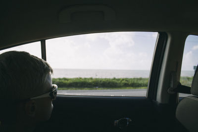 Rear view of boy sitting in car window
