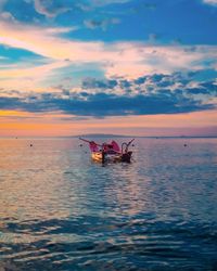 Boat in sea against sky during sunset