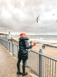 Rear view of man looking at sea against sky