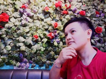 Portrait of woman looking at red flowering plants