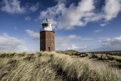 Lighthouse on field against sky