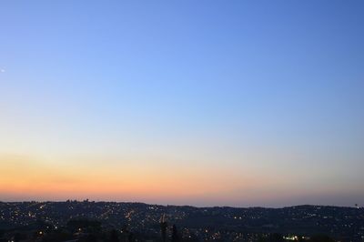Distant view of cityscape against clear sky during sunset