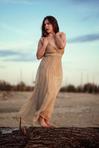 Beautiful young woman standing on land against sky