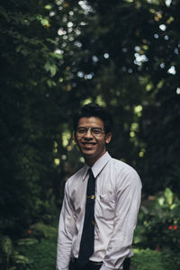 Portrait of young man standing against plants