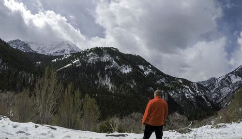 Rear view of man standing against mountain during winter