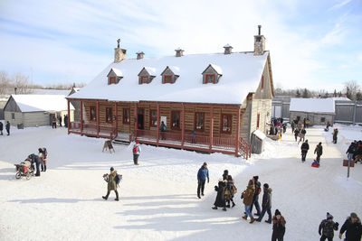 People on snow covered landscape against sky