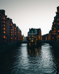 River amidst buildings against clear sky at dusk