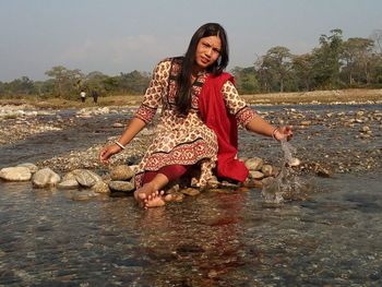 Full length of woman sitting by river