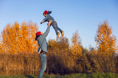 Portrait of a village boy child and father in red hats throws up into the sky