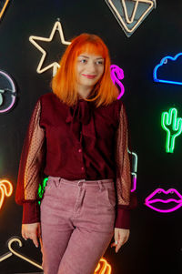 Portrait of young woman standing against wall